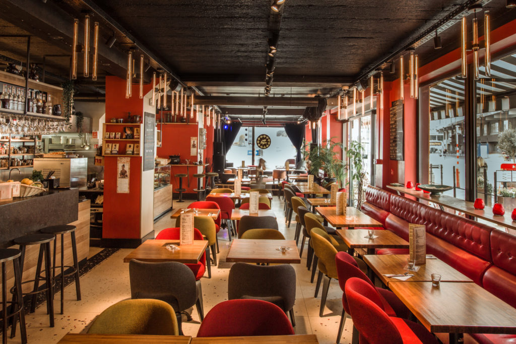 aménagement intérieur de restaurant avec bar sur la gauche, tables au centre et banquettes sur la droite.