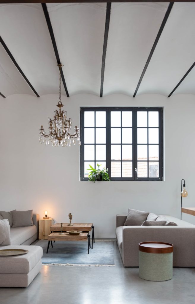 salon dans une ancienne fabrique rénovée avec sol en béton ciré et fenêtres industrielles